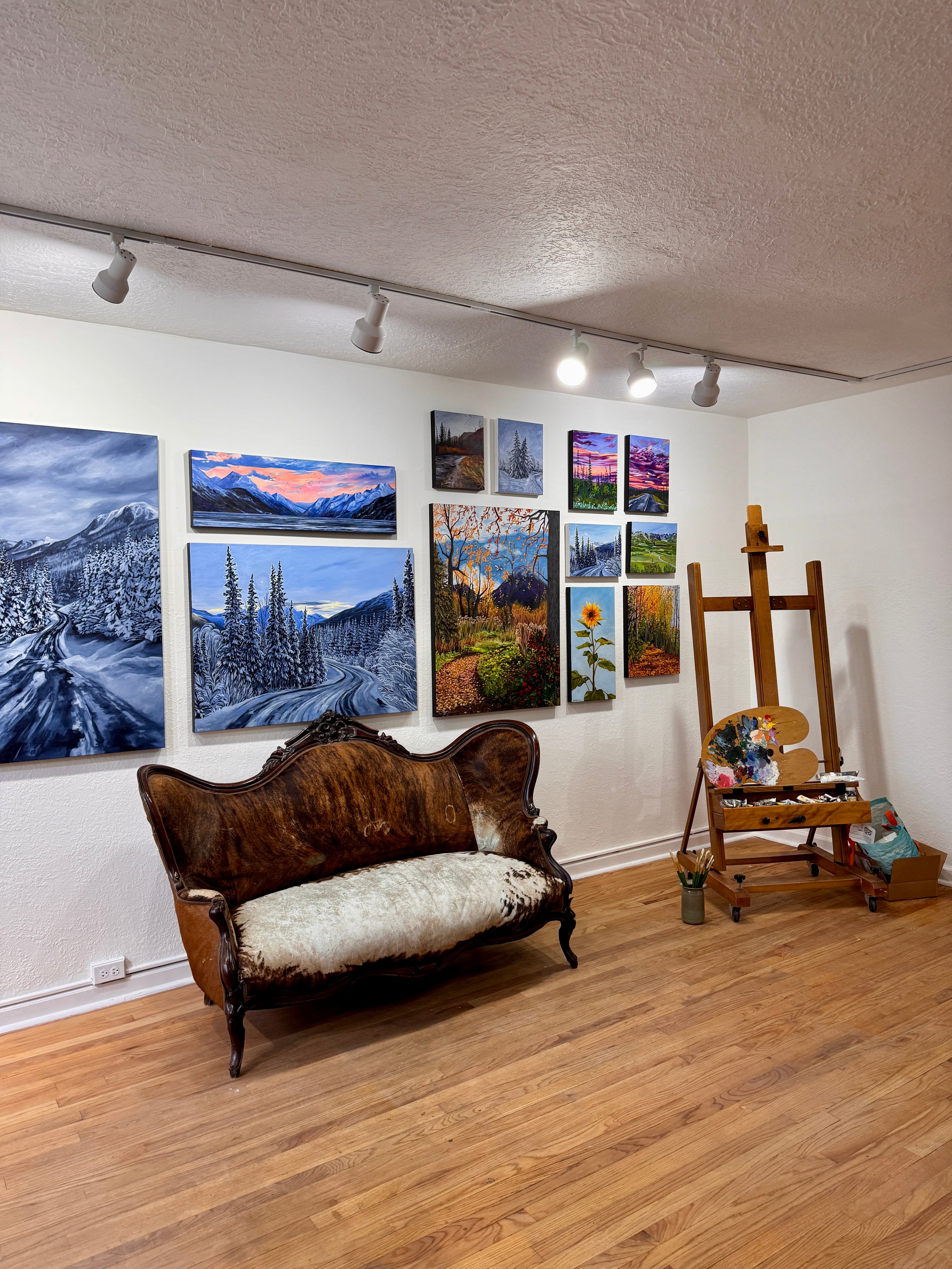 Antique couch sitting in art gallery, with Alaskan landscape paintings behind it, by artist AnnMarie Henderson